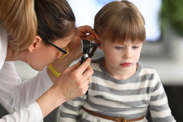 Kvinna otorhinolaryngologist undersöker små flickor öra med otoskop på kliniken — Stockfoto