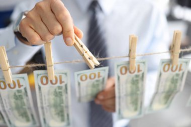 İş adamının eli, çamaşır mandallarıyla ipe Amerikan doları bağlıyor.