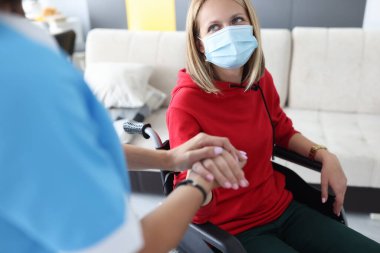 Doktor psikoterapist engelli genç kadının elini tutuyor.