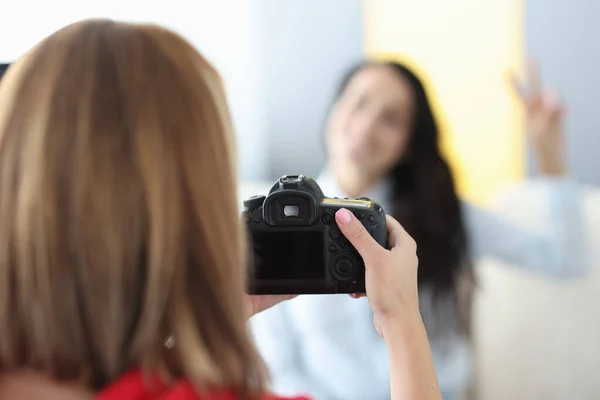 Czarny aparat fotograficzny w rękach kobiety fotograf z modelką na tle w studiu fotograficznym — Zdjęcie stockowe