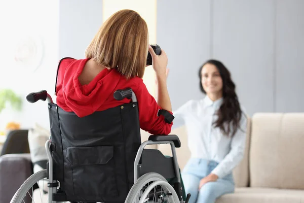 Жінка-фотограф в інвалідному візку фотомодель на задньому плані в фотостудії крупним планом — стокове фото