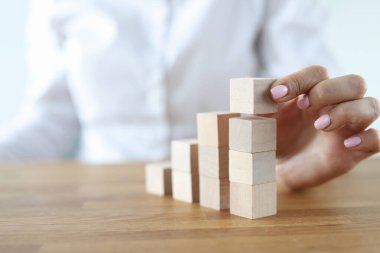 Kadın, yakın plan masa üzerine tahta küplerden kule inşa ediyor..