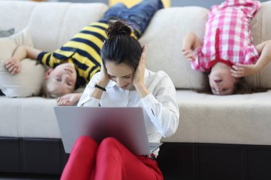 Yorgun kadın koltuğun yanına oturur, kulaklarını avuçlarıyla kapatır..