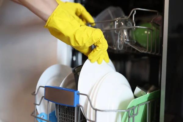 Mão na luva amarela tirar utensílio de cozinha lavado. — Fotografia de Stock