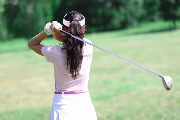 Žena v obleku drží golfovou hůl za zády. — Stock fotografie