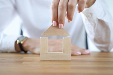 Masanın üzerine tahta küplerden ev yapan bir kadın..