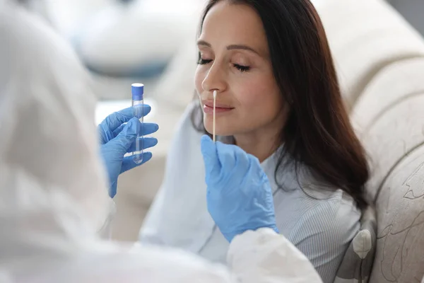 Médico assistente de laboratório em terno de proteção leva cotonete do nariz do paciente doente em casa — Fotografia de Stock