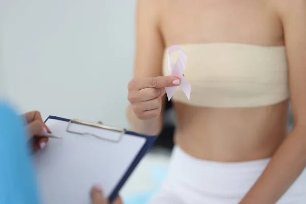 Žena pacient drží růžovou pásku v ruce v blízkosti mamolog s klipem detailní — Stock fotografie