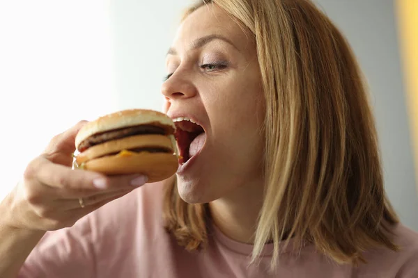 Mujer joven muerde su boca hamburguesa abierta — Foto de Stock