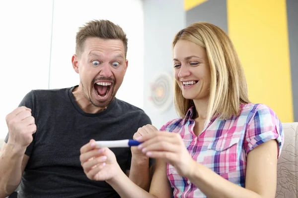 Marido sonriente y esposa están mirando la prueba de embarazo —  Fotos de Stock