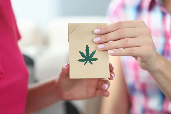 Female hands hold package with hemp leaves close-up
