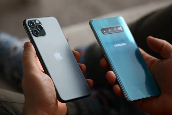 Homme tenir nouveau modèle pomme iphone et samsung dans la main gros plan — Photo