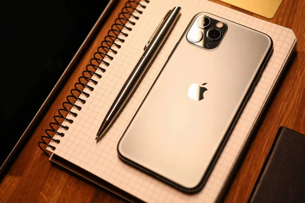 Nuevo modelo de Apple iphone se encuentra en el portátil con un bolígrafo en la oficina — Foto de Stock