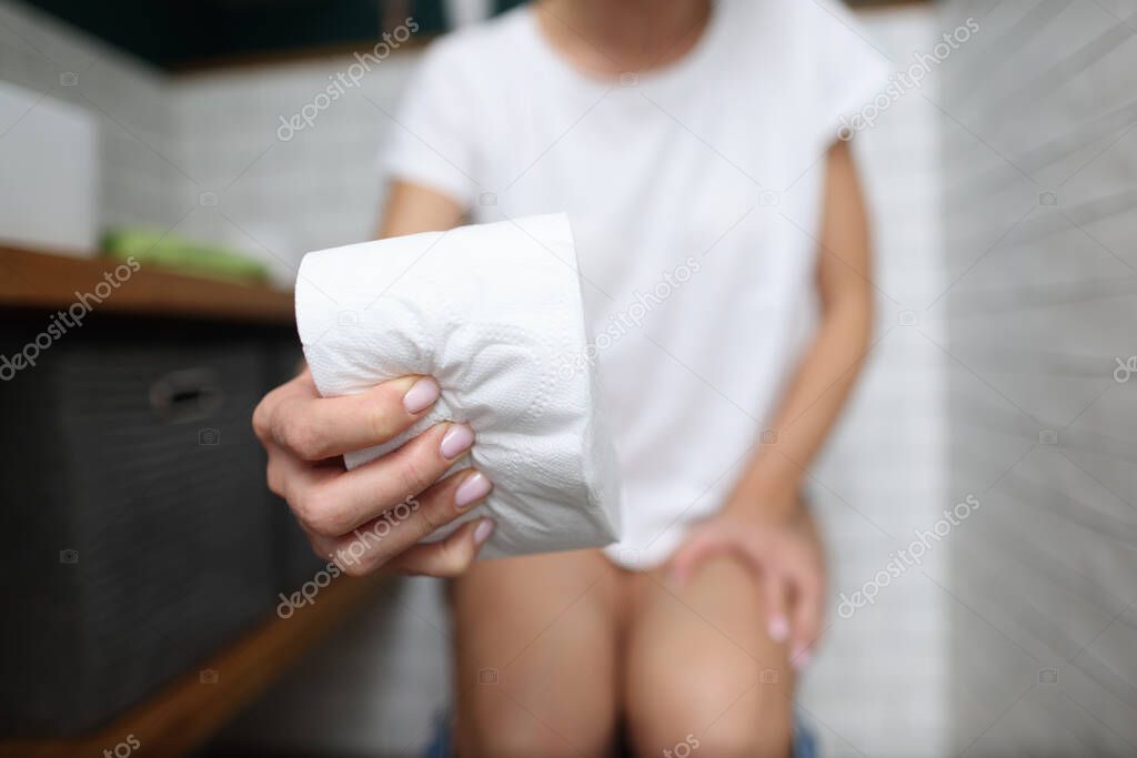 Womans hand squeezes roll of toilet paper in toilet close-up