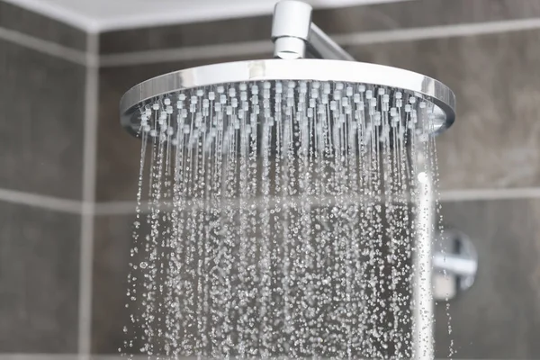 Close-up de água que flui da cabeça do chuveiro de chuva no banheiro — Fotografia de Stock