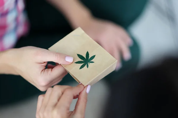 Kvinnlig hand håller papperspåse med en bild av marijuana symbol närbild. — Stockfoto