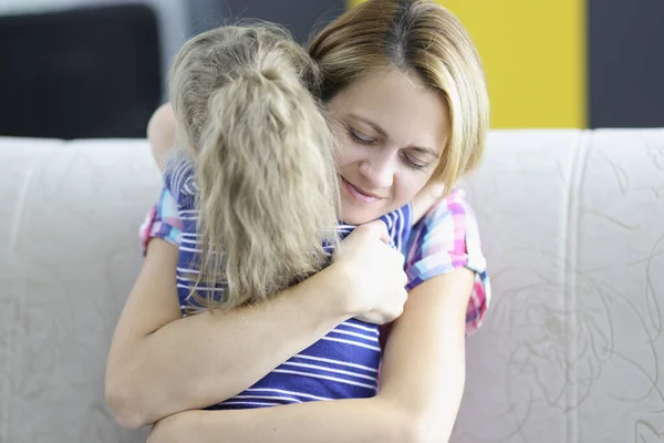 Niña con mamá abrazándose en el sofá en casa. —  Fotos de Stock