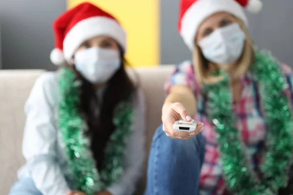 Mulher em santa claus chapéu sentar lado a lado no sofá. — Fotografia de Stock