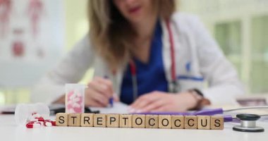 Streptococcus, hapların ve steteskopun yanında bulunan tahta küplerle oluşmuştur. Araçlar ve görüntüler bakteri araştırmaları ve boğaz enfeksiyonu riskine işaret ediyor.