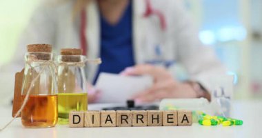 Doktor, masasında renkli ilaç sıvıları ve küplerin üzerindeki ishalle ilgili kağıtları inceliyor. Gastrointestinal sağlık sorunlarının ele alınmasının önemi