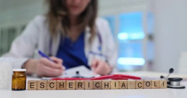 Escherichia Coli yakınlarında masa başındaki tahta bloklarda kadın tıbbi uzmanlar belgeleri inceliyor. Bakteriyel enfeksiyonların teşhis tedavisi