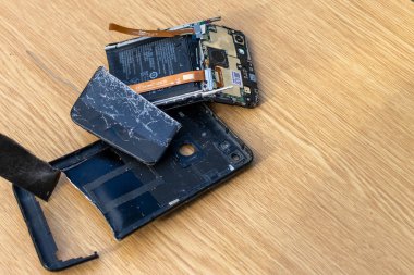 Hafif arka planda kırık ekran cep telefonu. Masanın üzerinde eski kırık siyah akıllı telefon. Cep telefonu onarım işlemini gösteren fotoğrafları kapatın. Akıllı telefon ve ahşap hummer. 