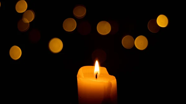 Candles Burning at Night. White Candles Burning in the Dark with focus on single candle in foreground.