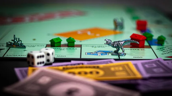 Closeup of board game Monopoly in Russian edition. Pieces from classical table game - money, houses, heroes, streets, dice