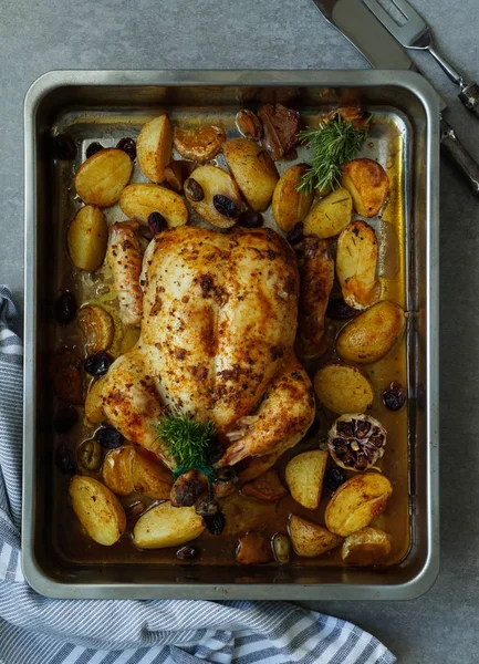 Baked turkey or juicy chicken with golden crispy skin with grapes and potatoes, tangerine. Roasted chicken in baking dish. Christmas dinner. Flat lay. Top view