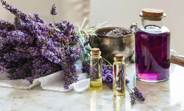 Botellas de aceite de lavanda, hierba natural cosmética consepto con flores de lavanda flatlay sobre fondo de piedra — Foto de Stock