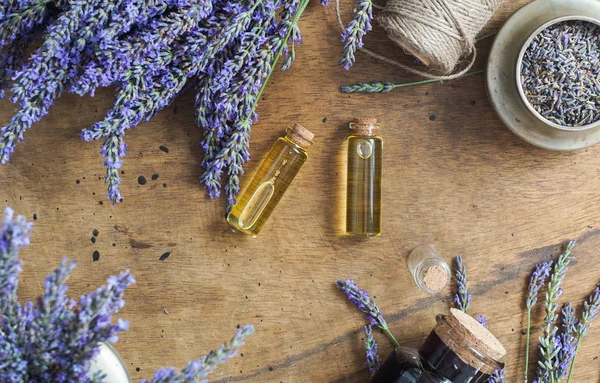 Botellas de aceite de lavanda, hierba natural cosmética consepto con flores de lavanda flatlay sobre fondo de piedra — Foto de Stock