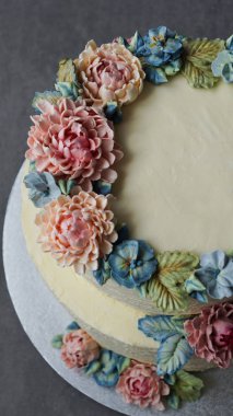 gri taş zemin üzerine buttercream çiçeklerle süslenmiş büyük düğün pastası