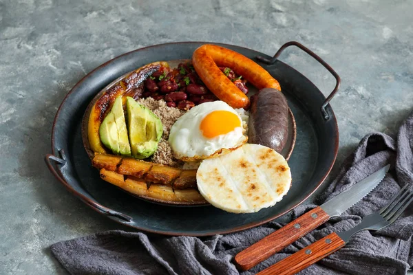 Comida colombiana. Bandeja paisa, plato típico de la región de Antioquia en Colombia - vientre de cerdo frito, budín negro, salchicha, arepa, frijoles, plátano frito, huevo de aguacate y arroz . — Foto de Stock