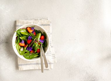 Taze yaz salatası ıspanak, çilek, soğan ve balzamik sirke ve yenilebilir çiçekler.;