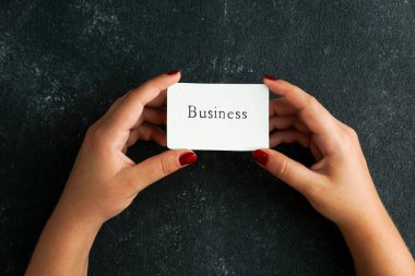 İş sözleşmesi, kadınların el ele tutuştuğu kartvizit, siyah somut arka planda.