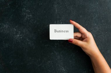 İş sözleşmesi, kadınların el ele tutuştuğu kartvizit, siyah somut arka planda.