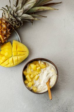 Sağlıklı kahvaltı, taze mangolu yoğurt ve hindistan cevizi kasesinde ananas.