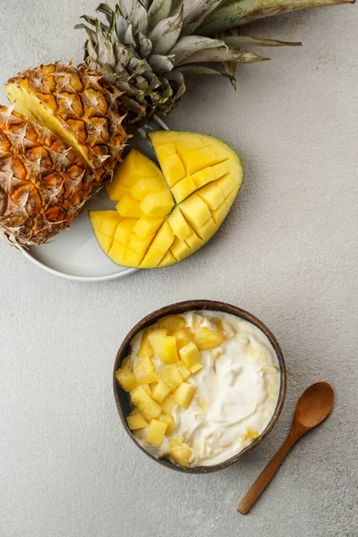 healthy breakfast consept, yogurt with fresh mango and pineapple in the coconut bowl