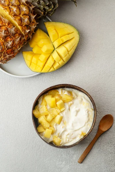 healthy breakfast consept, yogurt with fresh mango and pineapple in the coconut bowl