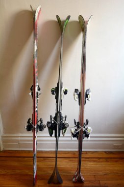 Three Pairs of Skis Leaning Against a Wall Indoors clipart