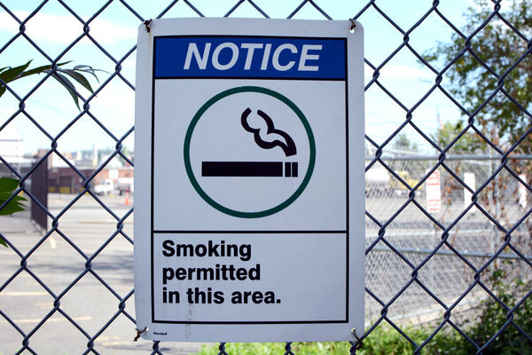 Smoking Permitted Sign on Fence at Designated Smoking Area