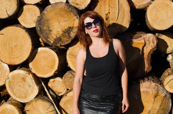 portrait of a red-haired girl near the logs