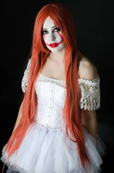 a girl in a clown costume with scary makeup on a black background