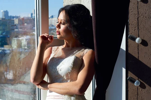 新娘站在窗边 看着照片 阳光照射下 — 图库照片
