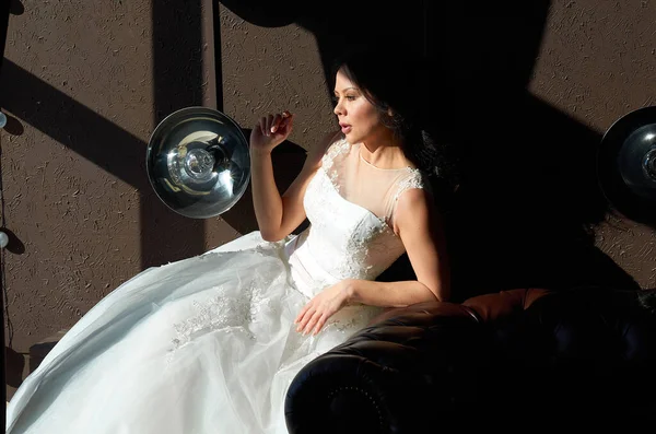 花嫁はソファに座って窓の外を見ています — ストック写真
