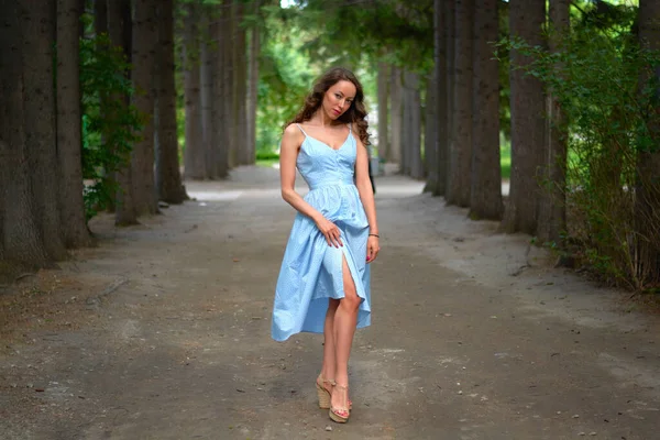 Piękna Dziewczyna Niebieskiej Sukience Stoi Drodze Park Curly Brunetka Przemyślaną — Zdjęcie stockowe
