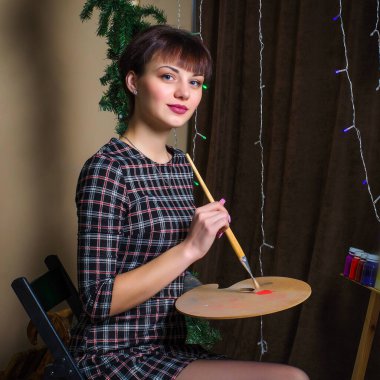 Elbiseli kısa saçlı bir kız yağlı boyalarla resim çizer..