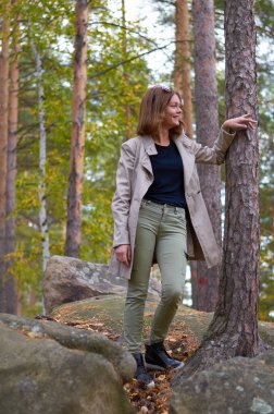 Bir kız sonbahar ormanındaki bir dağda duruyor..