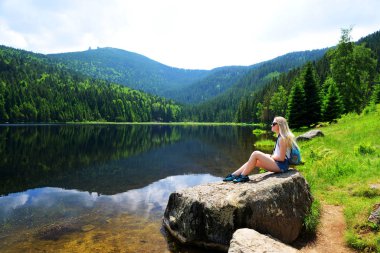 Kleiner Arbersee Milli Parkı Bavyera Ormanı içinde taş buzultaş gölün yanında oturan turist. Almanya.