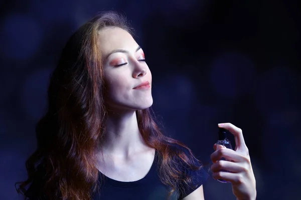 Joven Hermosa Mujer Sosteniendo Botella Perfume Aplicándolo Sobre Fondo Oscuro — Foto de Stock